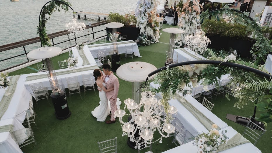 A couple at a waterfront reception dressed with chandeliers and florals